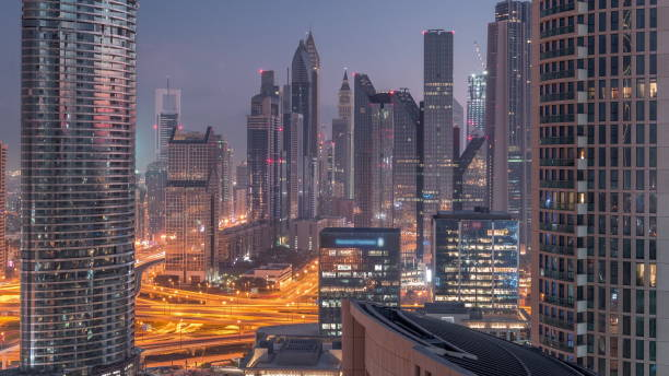 vue aérienne de nouveaux gratte-ciel et de grands bâtiments dans le timelapse de dubaï de nuit en jour - night cityscape dubai long exposure photos et images de collection