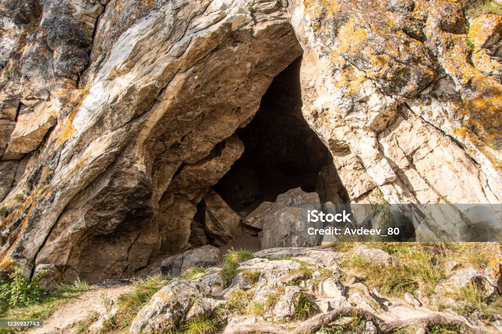 small cave or grotto in mountain cliff, mountaineering and caving in rocks Cave Stock Photo