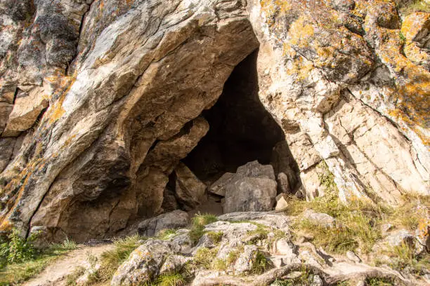 Photo of small cave or grotto in mountain cliff, mountaineering and caving in rocks