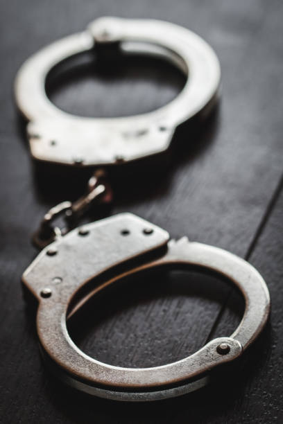 istock steel metal Handcuffs on brown background 1235948986