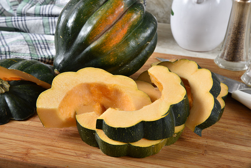 Closeup of sliced uncooked acorn squash on a cutting board