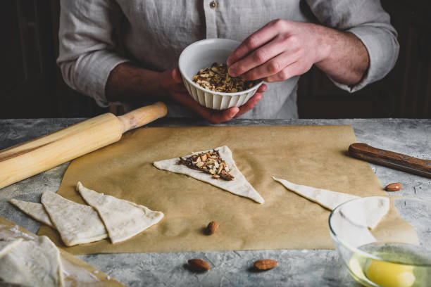 istock Croissant preparing. Baker sprinkles chopped almonds on top of hazelnut spread 1236035158