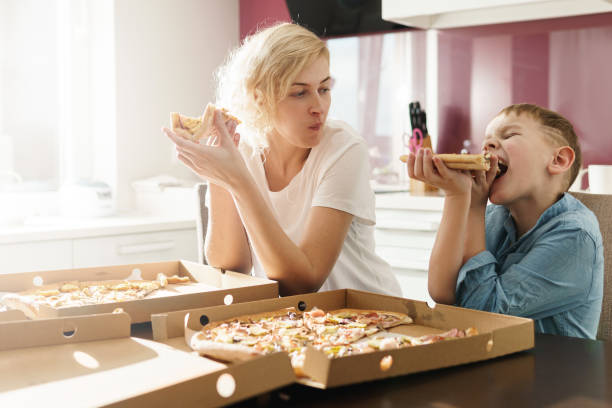 istock Mother and her cute son eating delicious pizza at home 1236053285