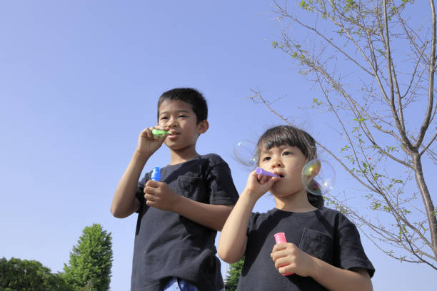 istock Japanese brother and sister playing with bubble under the blue sky (10 years old boy and 5 years old girl) 1236059104
