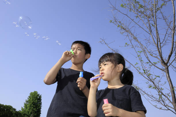 istock Japanese brother and sister playing with bubble under the blue sky (10 years old boy and 5 years old girl) 1236059639