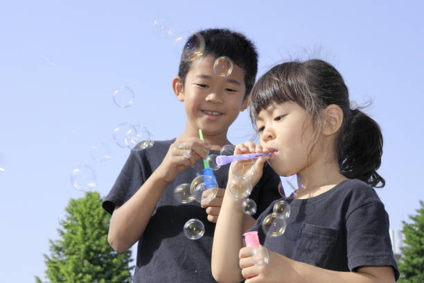 istock Japanese brother and sister playing with bubble under the blue sky (10 years old boy and 5 years old girl) 1236059848