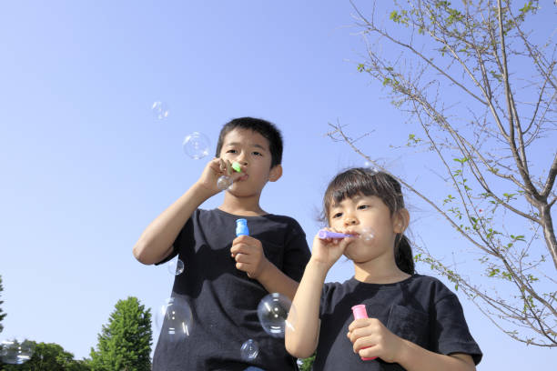 istock Japanese brother and sister playing with bubble under the blue sky (10 years old boy and 5 years old girl) 1236061362