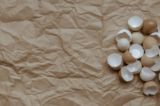 istock Texture of broken empty eggshell on a crumpled brown kraft paper background. View from above. Copyspace. 1236077658
