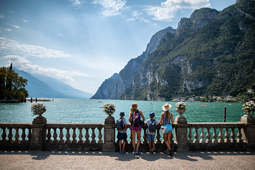 Family enjoying vacations in Italy. They are walking in the promenade of of Riva del Garda and enjoying view of Lake Garda surrounded my mountains.\nNikon D850