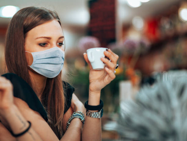 istock woman at the cafe drinking a coffee with face mask 1236261233
