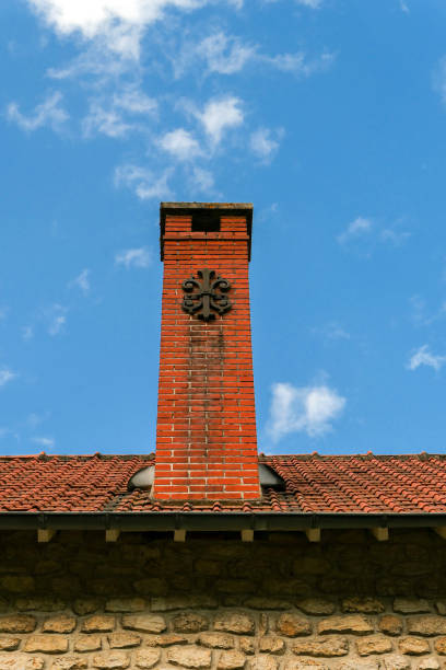 Masonry structure for the evacuation of a heating system. Wrought iron decoration with a rounded shape.