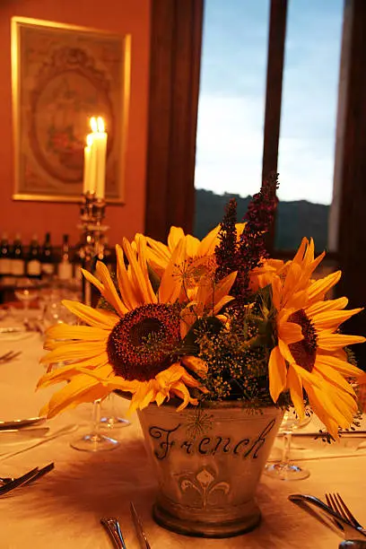 romantic dinnertable with warm colors. sunflowers en set table with bottles of wine in the back