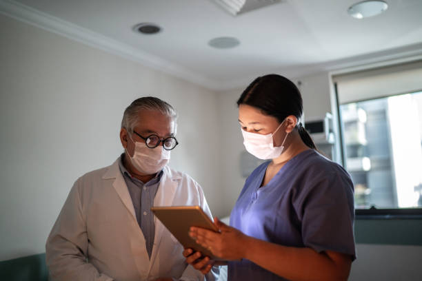 istock Healthcare workers talking and using digital tablet with face mask in hospital 1236323226