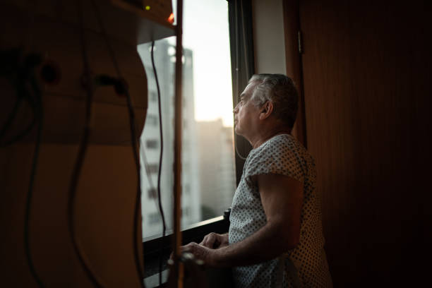senior-patient schaut durch fenster im krankenhaus - alzheimer krankheit stock-fotos und bilder