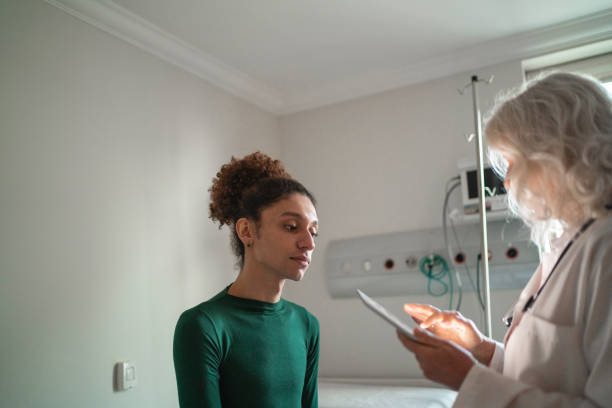 arzt im krankenhauszimmer mit digitalem tablet im gespräch - trans stock-fotos und bilder