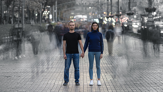 The man and woman stand on the crowded street and hold hands