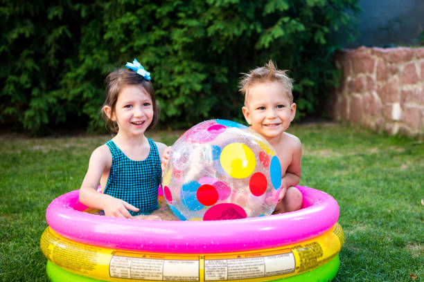 istock Two children with beach ball at swimming pool. Joyful kid playing in inflatable pool backyard. Little kids at swimming pool on sunny day. Colorful swimming pool ball. Healthy babies summer activity 1236363659