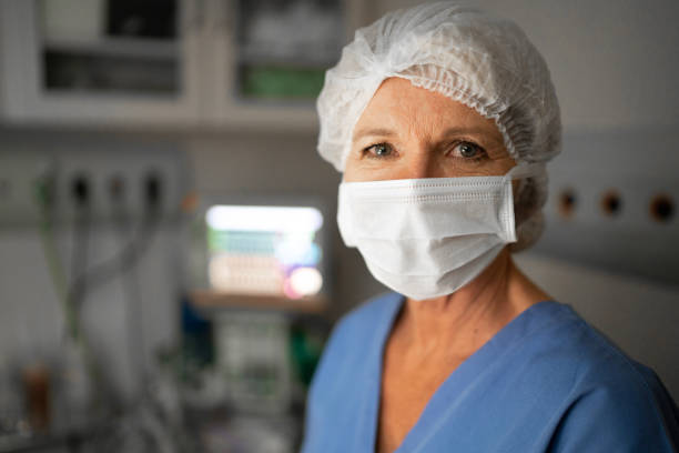 retrato de una trabajadora sanitaria con mascarilla facial en el quirófano del hospital - women mature adult working doctor fotografías e imágenes de stock