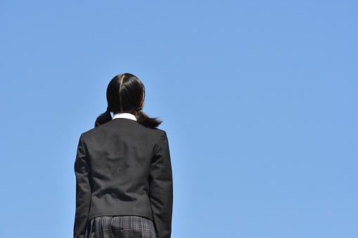 Chica japonesa de pie en la vista trasera del cielo azul photo