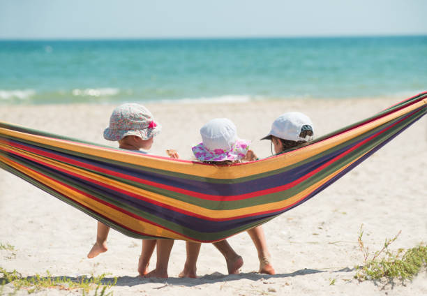 Children have a rest in a hammock on a sandy seashore