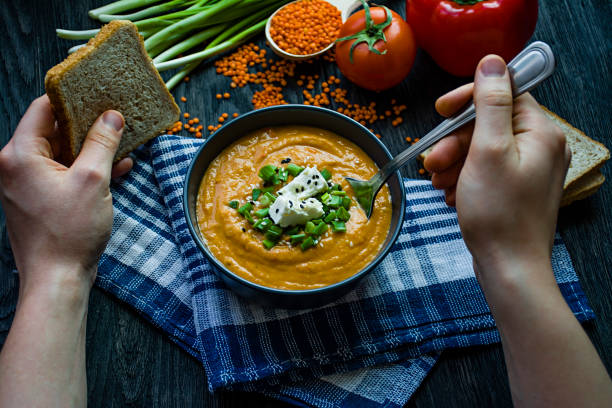 istock Red lentil cream soup decorated with fresh vegetables and herbs. A man eats soup. Veggie concept. Proper nutrition. 1236467912
