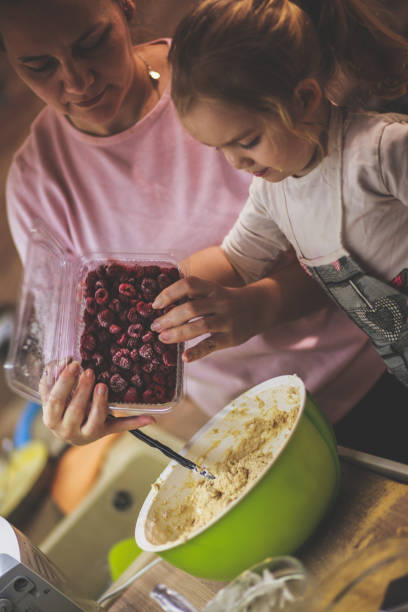 istock Toddler assisting her mother in adding fresh cherries into a cheesecake batter 1236469543