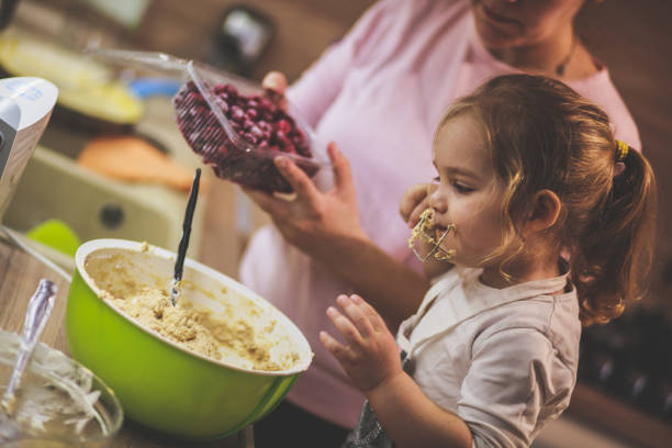 istock Little girl licking the whisk while making a cheesecake with her mom 1236469546