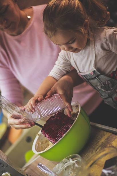 istock Three year old helping her mother add the cherries into a cheese cake batter 1236469548