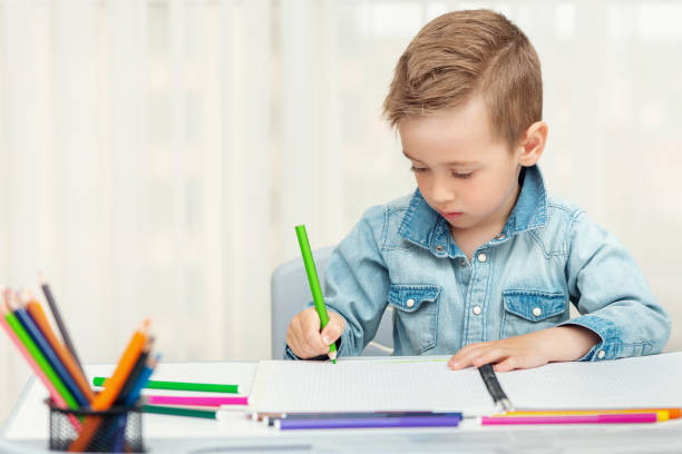 istock Little boy doing homework writing and painting. 1236476153