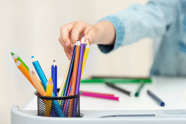 Child takes a pencil for drawing, the kid's workplace, the concept of developing creativity, close up.