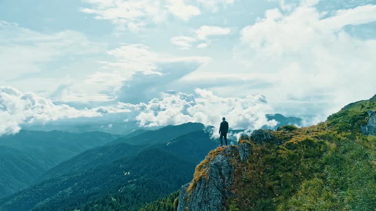 The man standing on the mountain cliff with a beautiful landscape