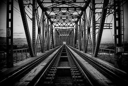 Taken on a train track at the start of a bridge in Osaka, near Kyoto. Shot towards sunset and in black and white to give it some extra mood and atmosphere. \nThis shot tries to give a sense of perspective and what looks like an endless horizon.