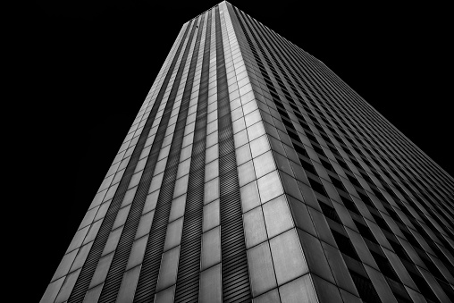 A black and white image of a modern office building taken from an angle to give a sense of perspective.