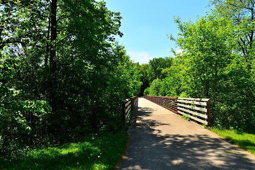 A sturdy walking and biking bridge in a forested area and over the Fox River in Rochester Wisconsin.