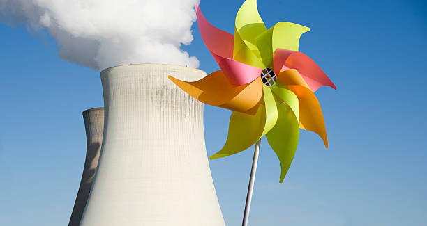 energia nucleare, vento contro - wind power toy symbol cooling tower foto e immagini stock