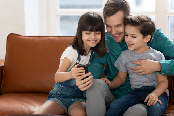 istock Happy dad and little kids have fun using cellphone together 1236697300