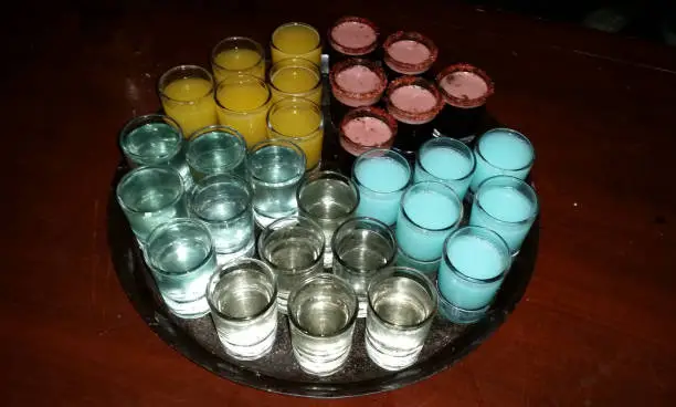Photo of Tray of various Mescal shots of various flavors on a wooden table