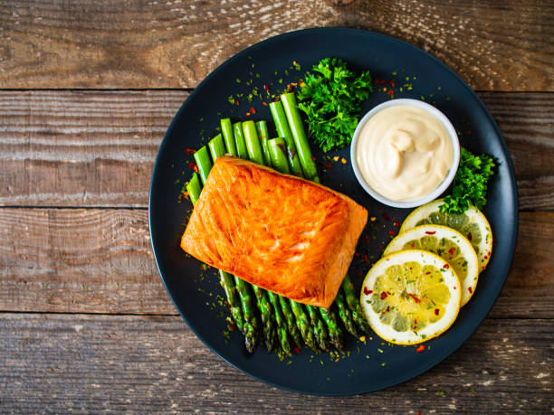 istock Fried salmon steak and asparagus on wooden table 1236801078