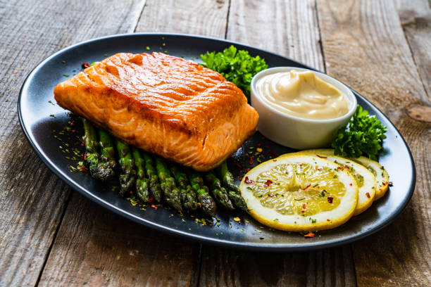 istock Fried salmon steak and asparagus on wooden table 1236802639
