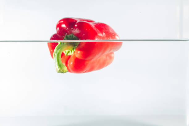 Shot of green and red peppers passing under sprinklers while on a conveyor belt in a processing plant