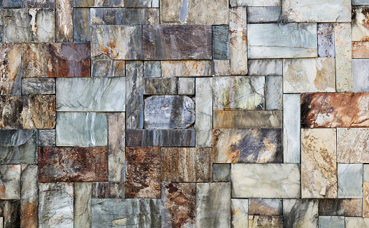 rough,  Modern gray brown, beige, metal door at the house lined with stone cladding. gutter for drainage of water on the pavement. limestone cladding