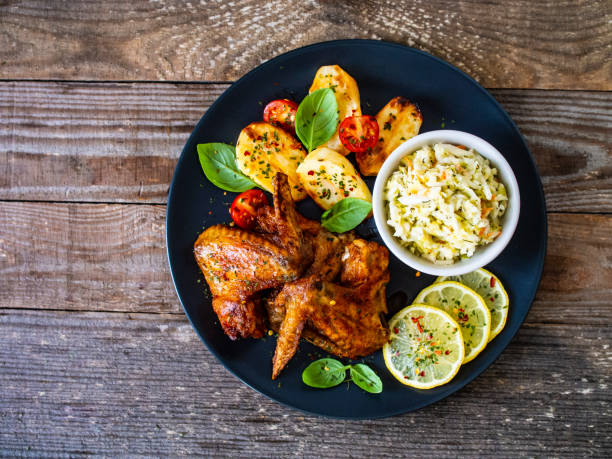 istock Roast chicken wings and vegetables served on wooden table 1236976170