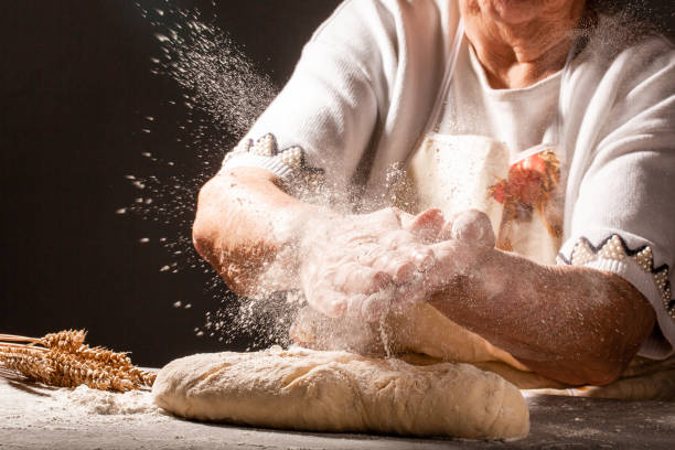 Photo of flour and old woman, grandmother hands with flour splash. Cooking bread. Kneading the Dough. Isolated on dark background. Empty space for text stock photo