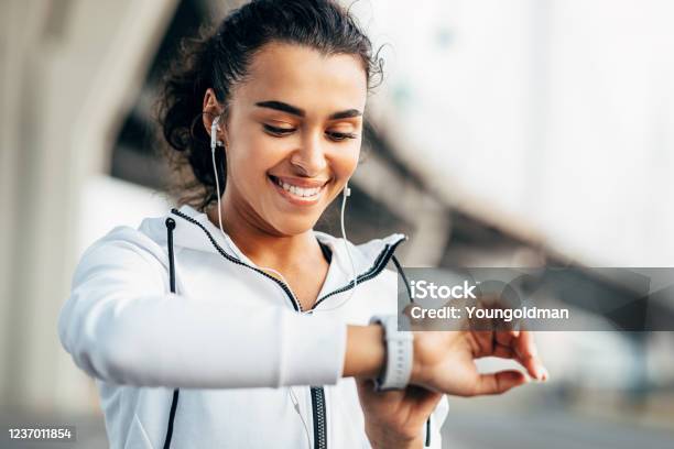 Smiling Woman Checking Her Physical Activity On Smartwatch Young Female Athlete Looking On Activity Tracker During Training Stock Photo - Download Image Now