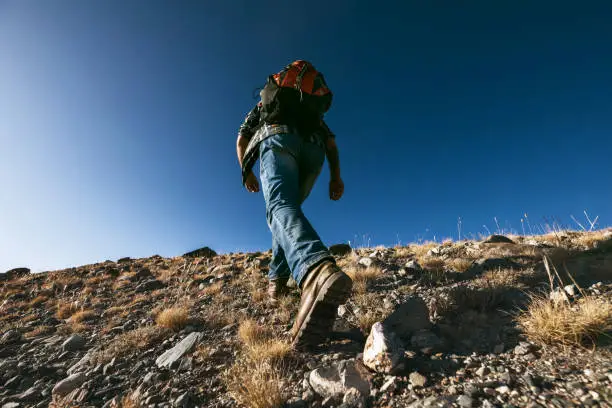 Photo of Unrecognizable male traveler goes uphill