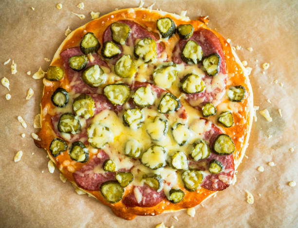 Simple homemade pizza with pickled cucumber cheese, sausages and cheese