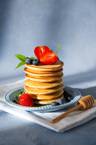 istock Homemade pancakes with strawberries and blueberries on blue background. 1237060367