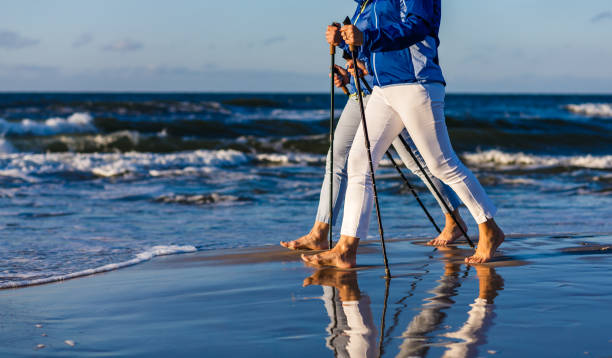 ノルディックウォーキング - ビーチで働くアクティブな人々 - nordic walking walking relaxation exercise women ストックフォトと画像