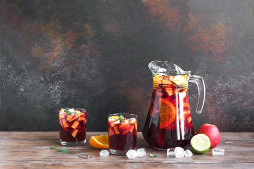 Red Wine Sangria in pitcher and glasses, copy space. Homemade refreshing drink - fruit sangria or punch.