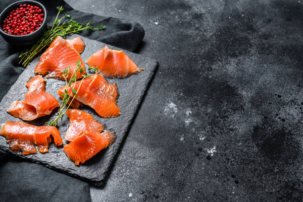 istock Salted salmon slices with pepper and thyme. Organic fish. Black background. Top view. Copy space 1237094471
